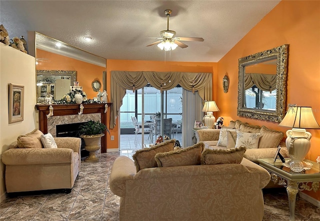 living room with ceiling fan, a fireplace, a textured ceiling, and vaulted ceiling