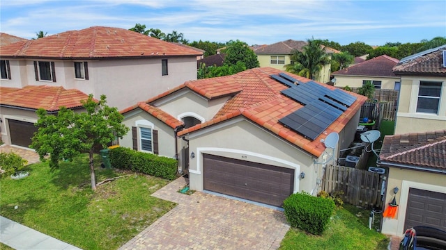 mediterranean / spanish house featuring a front lawn and solar panels