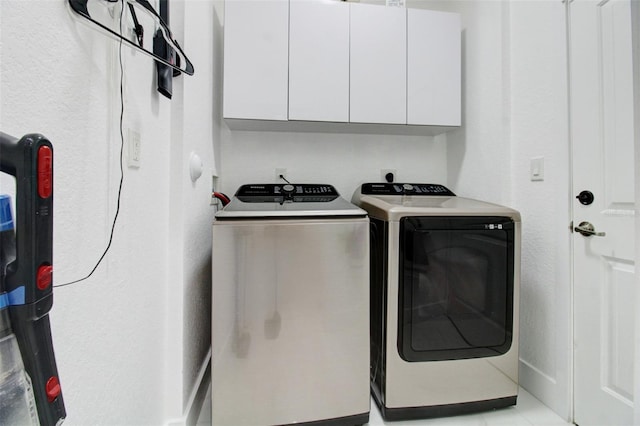 washroom with cabinets, light tile patterned floors, and washer and dryer