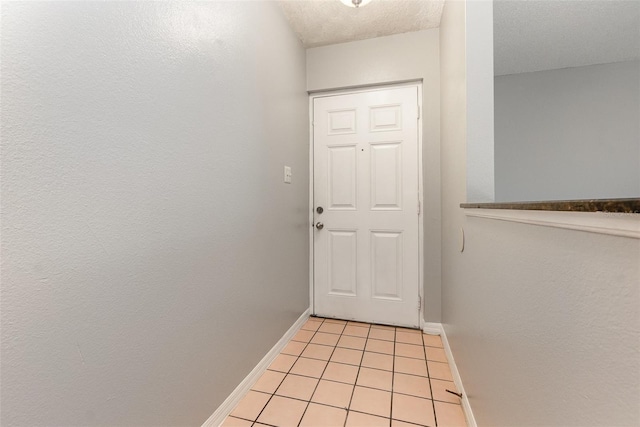 doorway with a textured ceiling and light tile patterned flooring