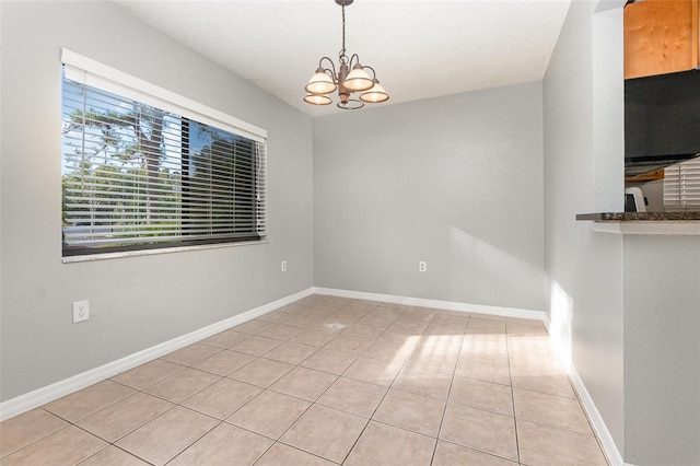 tiled empty room featuring a chandelier