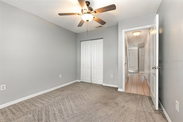 unfurnished bedroom with ceiling fan, a closet, carpet floors, and a textured ceiling