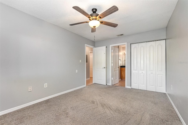 unfurnished bedroom featuring light carpet, a textured ceiling, a closet, and ceiling fan