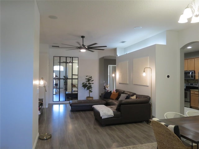 living room with ceiling fan with notable chandelier and dark hardwood / wood-style floors