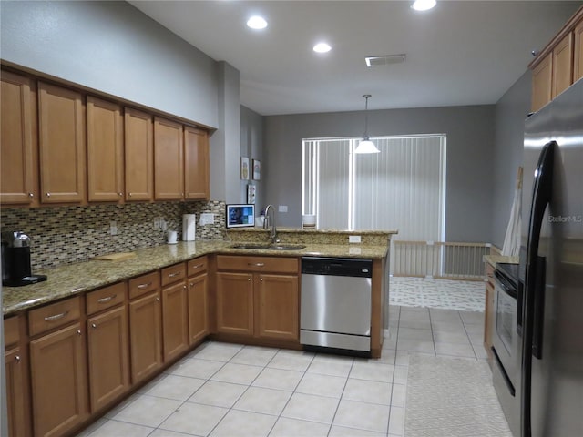 kitchen with sink, light tile patterned floors, appliances with stainless steel finishes, decorative light fixtures, and kitchen peninsula