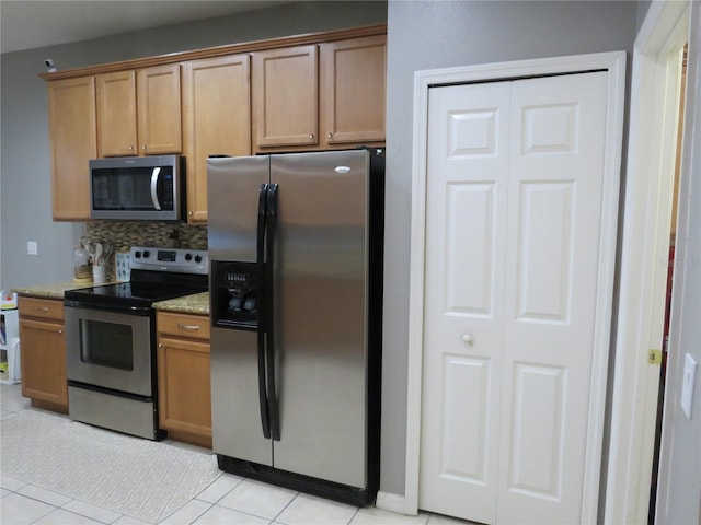 kitchen featuring backsplash, light stone counters, light tile patterned floors, and stainless steel appliances