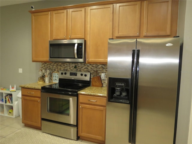 kitchen featuring light stone countertops, appliances with stainless steel finishes, tasteful backsplash, and light tile patterned floors