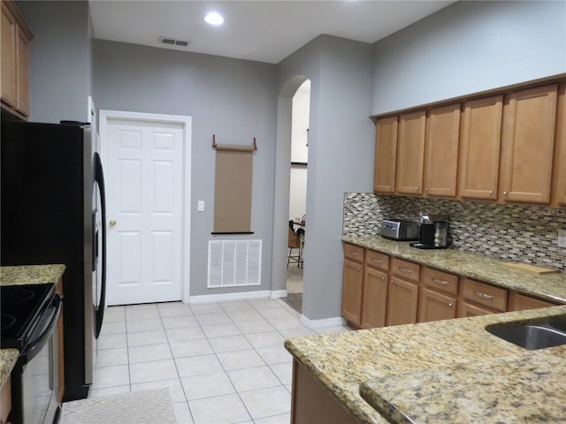 kitchen with sink, light stone counters, black electric range, decorative backsplash, and light tile patterned flooring