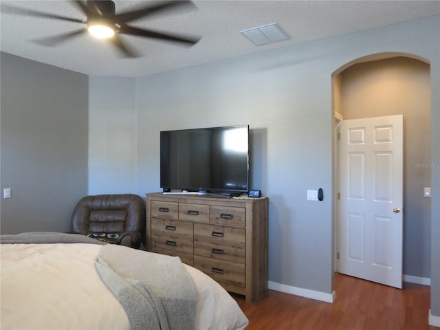 bedroom featuring a textured ceiling, ceiling fan, and dark wood-type flooring