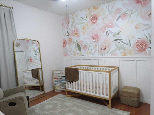 bedroom with hardwood / wood-style flooring and a nursery area