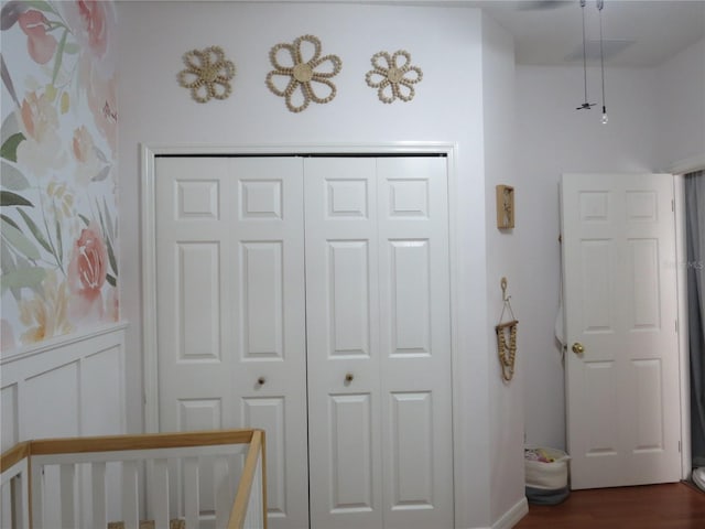 bedroom featuring a closet, a nursery area, and dark wood-type flooring