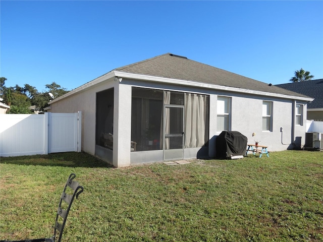 back of house featuring central AC unit, a lawn, and a sunroom