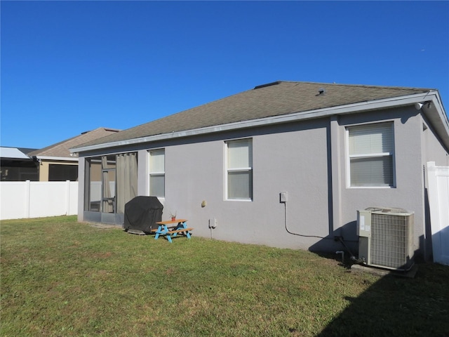 rear view of house with a yard, central AC unit, and a sunroom