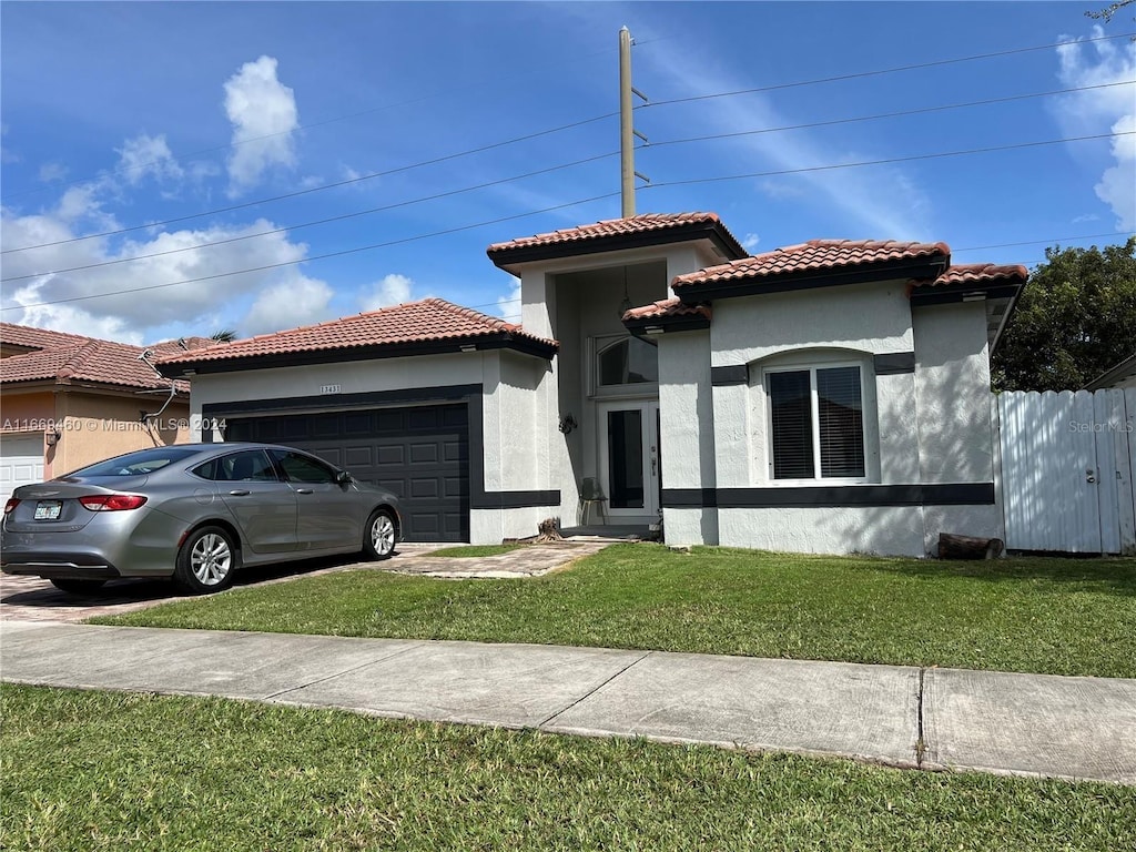 mediterranean / spanish-style house featuring a garage and a front yard