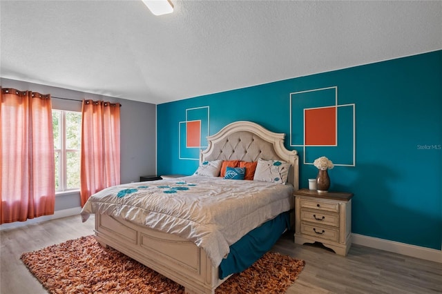 bedroom with a textured ceiling and light hardwood / wood-style flooring