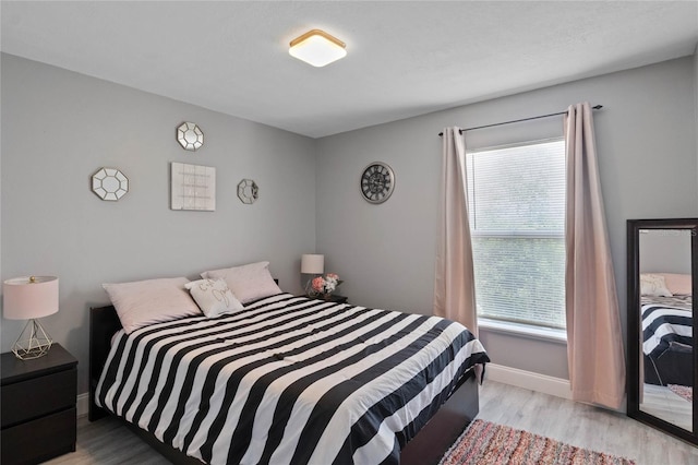 bedroom with light hardwood / wood-style floors and multiple windows