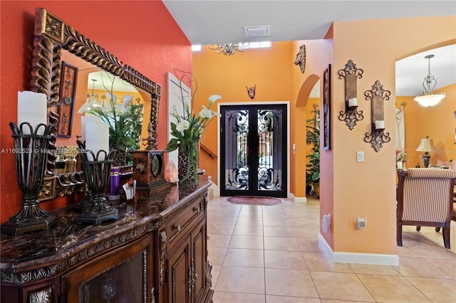 tiled entrance foyer with french doors and a chandelier