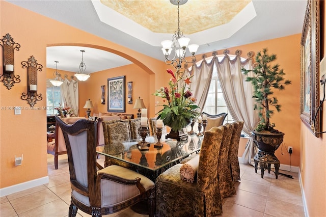 tiled dining area with an inviting chandelier and a tray ceiling