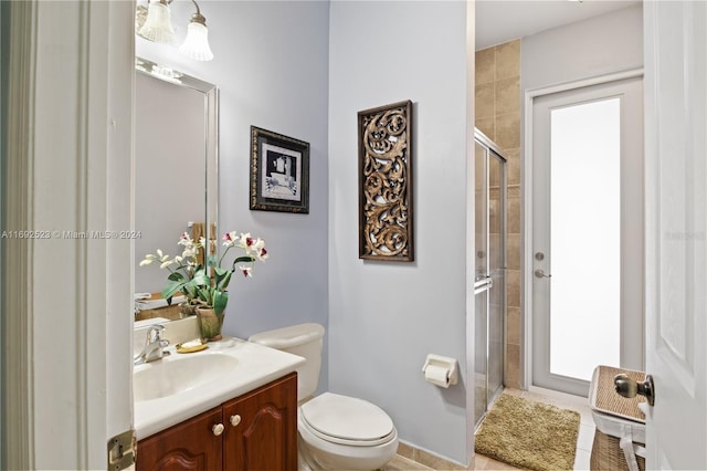 bathroom featuring toilet, a shower with door, tile patterned floors, and vanity