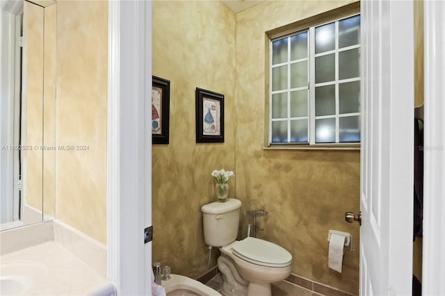 bathroom with toilet, tile patterned flooring, and a bidet