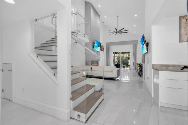 stairway with ceiling fan and high vaulted ceiling