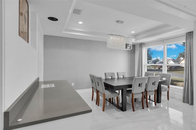 dining area featuring a raised ceiling and a notable chandelier