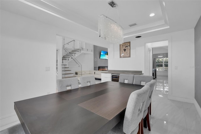 dining area with wine cooler, a tray ceiling, and an inviting chandelier