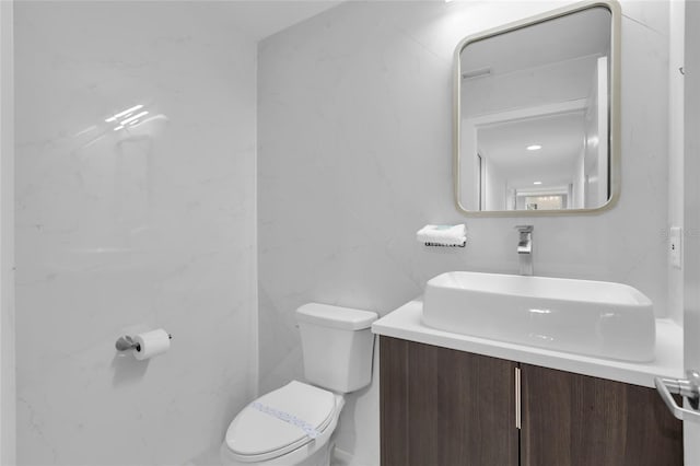 bathroom featuring vanity, toilet, and tile walls