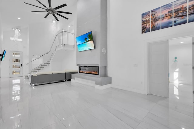 unfurnished living room featuring ceiling fan and a towering ceiling