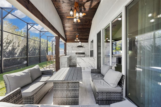 view of patio featuring sink, an outdoor hangout area, glass enclosure, and exterior kitchen