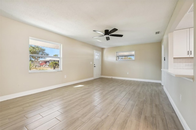 unfurnished room with ceiling fan, a textured ceiling, and light hardwood / wood-style flooring