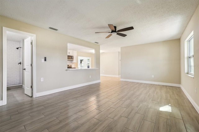 unfurnished living room featuring a textured ceiling, light hardwood / wood-style flooring, and ceiling fan