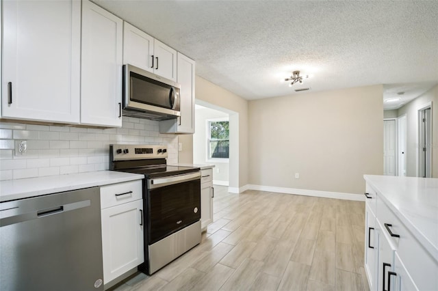 kitchen featuring white cabinets, light hardwood / wood-style flooring, a textured ceiling, appliances with stainless steel finishes, and tasteful backsplash