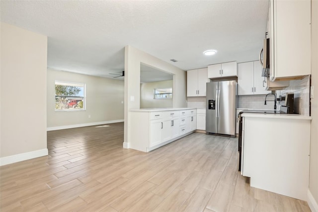 kitchen with appliances with stainless steel finishes, a textured ceiling, ceiling fan, light hardwood / wood-style flooring, and white cabinetry