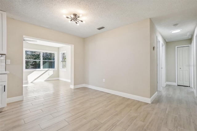 empty room with light hardwood / wood-style floors and a textured ceiling