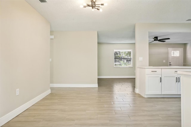 interior space featuring ceiling fan with notable chandelier, a textured ceiling, and light hardwood / wood-style flooring