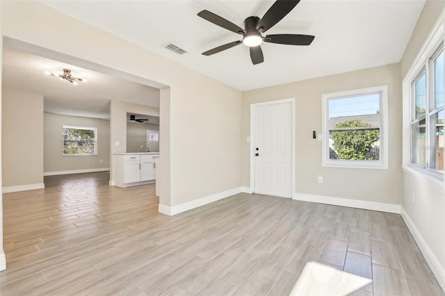 empty room with ceiling fan and light hardwood / wood-style flooring