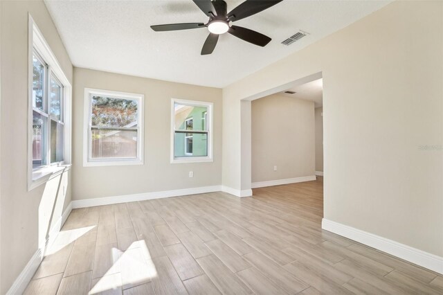 empty room featuring a textured ceiling, light hardwood / wood-style flooring, and ceiling fan