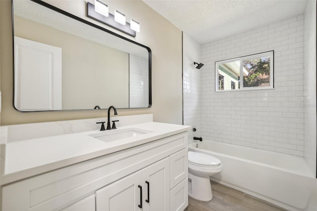 full bathroom with vanity, a textured ceiling, hardwood / wood-style floors, toilet, and tiled shower / bath