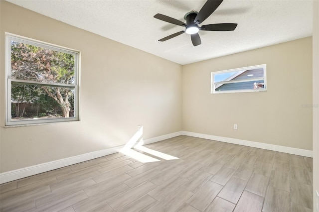 spare room with ceiling fan, light wood-type flooring, and a textured ceiling