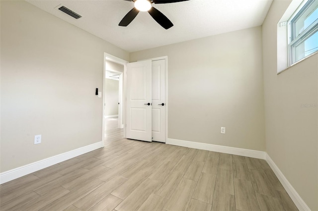 empty room featuring ceiling fan, light hardwood / wood-style floors, and a textured ceiling