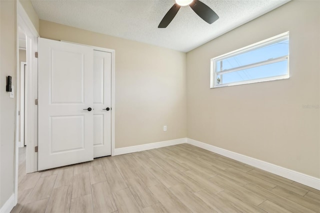 unfurnished bedroom featuring ceiling fan, a closet, a textured ceiling, and light hardwood / wood-style flooring