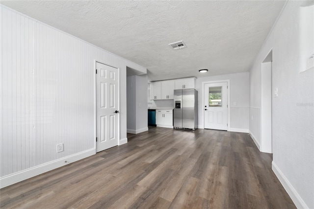 unfurnished living room with dark hardwood / wood-style flooring and a textured ceiling