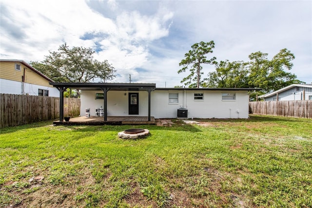 back of property featuring central AC, a yard, and a fire pit