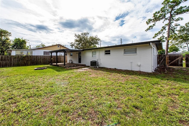 rear view of property with a patio area, a yard, and central AC