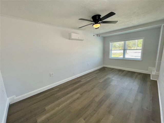 empty room with a wall mounted AC, ceiling fan, dark wood-type flooring, and a textured ceiling