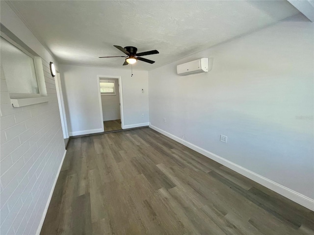 empty room with ceiling fan, dark hardwood / wood-style flooring, brick wall, a wall unit AC, and a textured ceiling