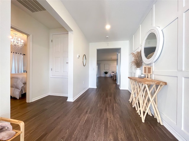 hallway featuring dark hardwood / wood-style floors and an inviting chandelier