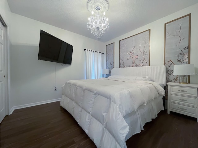 bedroom featuring a textured ceiling, dark hardwood / wood-style floors, and an inviting chandelier