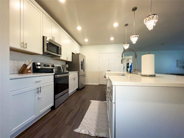 kitchen featuring dark wood-type flooring, tasteful backsplash, pendant lighting, white cabinets, and appliances with stainless steel finishes